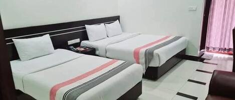 A hotel room with two beds, a nightstand, a chair, and a painting on the wall.