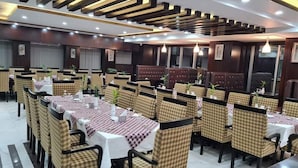 A restaurant with checkered chairs and tables, wooden paneling, and pendant lighting. - Elaf International Cox's Bazar (Cox's Bazar)
