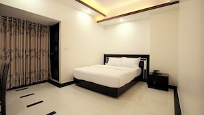 A modern bedroom with a large bed, a nightstand, and a chair. - Elaf International Cox's Bazar (Cox's Bazar)