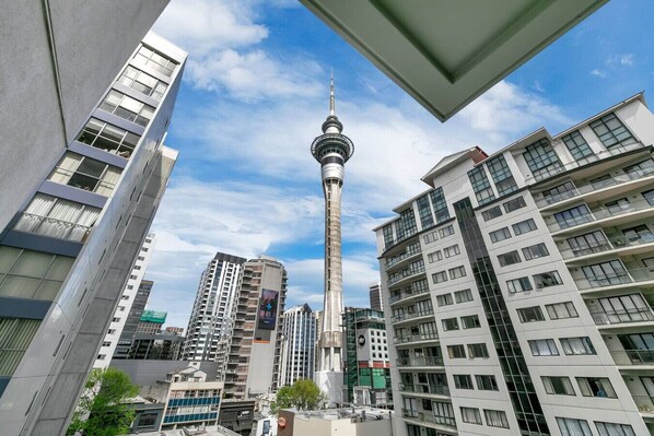 A modern urban skyline with high-rise buildings, a prominent tower, and a clear blue sky.