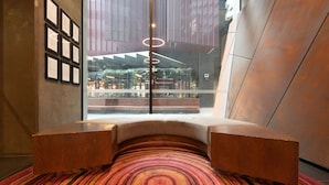 Un intérieur moderne avec un espace salon central, une moquette à motifs et une vue sur un espace extérieur grâce à un mur de verre.