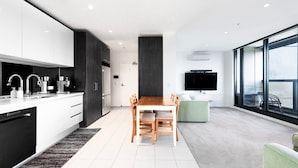 Une cuisine moderne avec des meubles blancs, un lave-vaisselle Bosch et un coin repas comprenant une table et des chaises en bois.