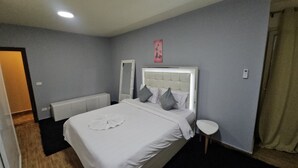 A bedroom with a bed, a bedside table, a mirror, and a radiator. - Midpoint sea view - families only (Alexandria)