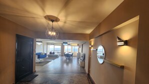 A hotel hallway with a modern design, including a black door, a dining area with a table and chairs, and a large mirror on the wall. - Midpoint sea view - families only (Alexandria)