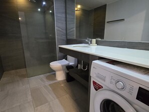 Une salle de bain moderne avec des toilettes blanches, un lave-linge et un évier.
