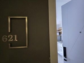 Une porte portant le numéro 621, qui donne sur une pièce aux murs blancs et dotée d’une étagère intégrée.