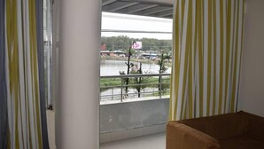 A room with a view of a lake, a balcony with a railing, and a striped curtain. - Hotel Marine Plaza (Cox's Bazar)