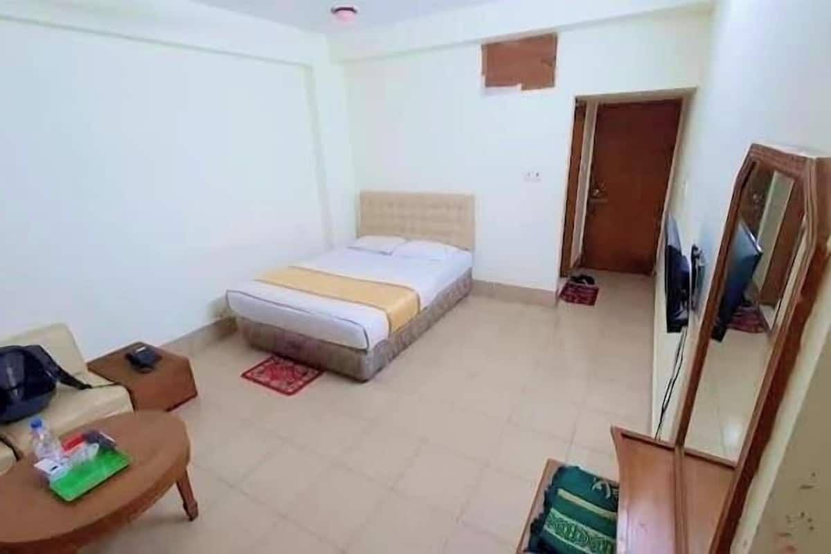 A hotel room with a bed, a sofa, a small table, and a TV.