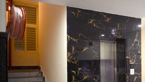 A modern elevator with marble walls, a staircase with grey steps, and a handrail. - Stanza Premium Hotels (Bhubaneshwar)