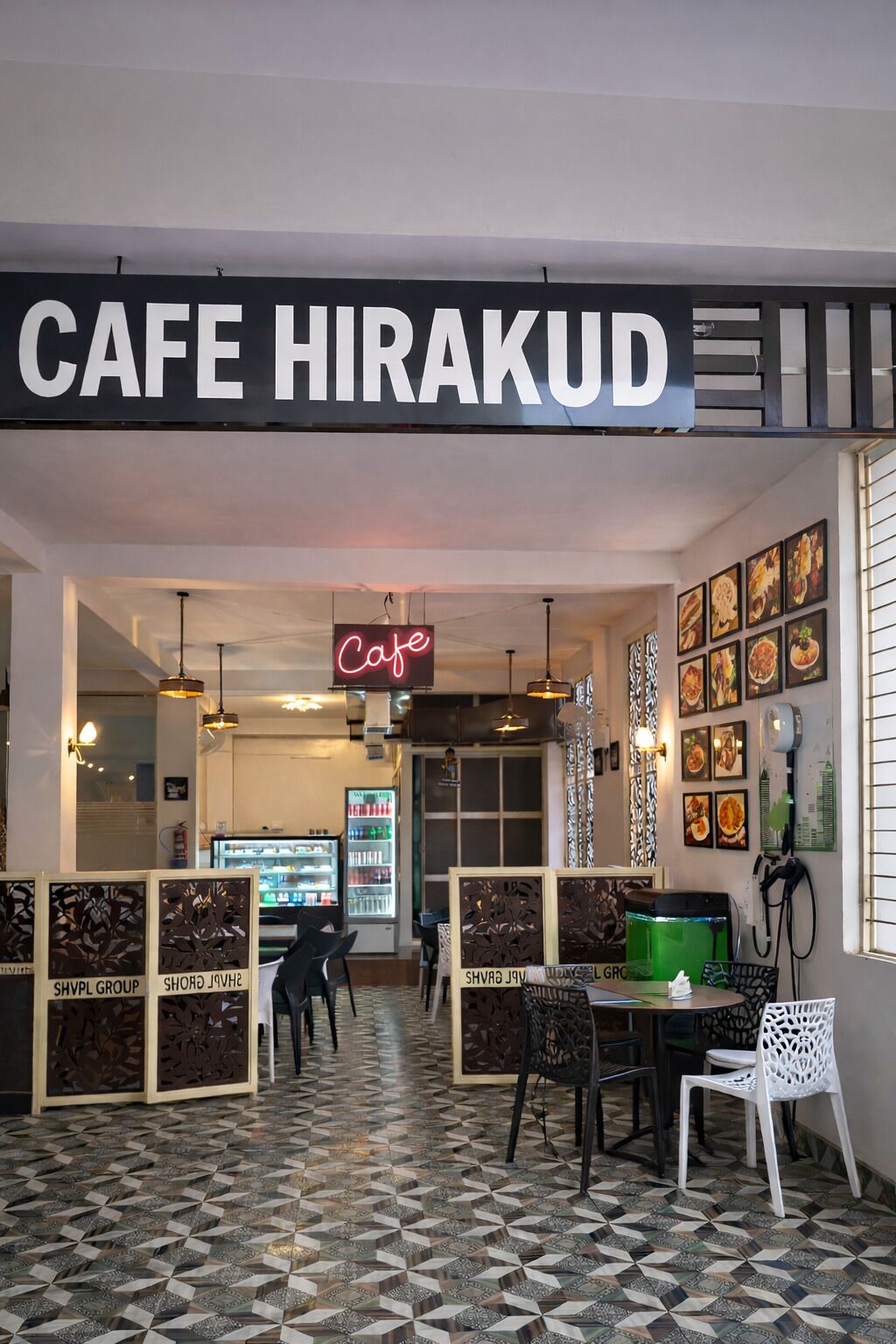 Ein Café-Interieur mit einem geometrisch gemusterten Boden, einer Neonreklame und einer Theke.