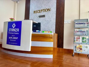 A reception desk with a 'RECEPTION' sign, a 'NO CASH ACCEPTED' notice, and a 'STANZA Premium Hotels' sign. - Stanza Premium Hotels (Bhubaneshwar)