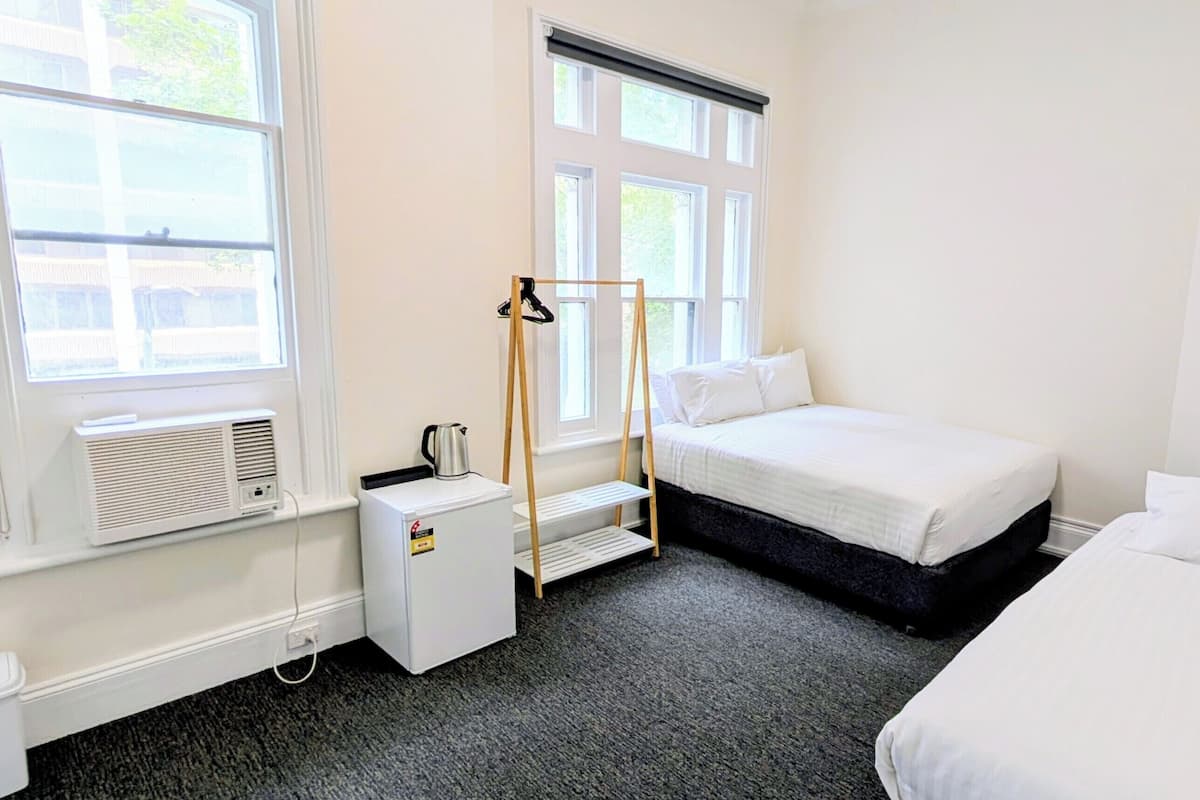 A small, clean room with a bed, a heater, and a window.