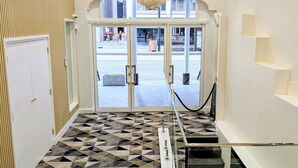 A hotel entrance with a geometric patterned floor, a chandelier, and a glass door leading to the street. - AMBASSADORS HOTEL ADELAIDE (Adelaide)