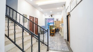 A staircase with black railings leading to a landing area with a tiled floor and a door. - Tamastu House Pasar Baru Jakarta (Jakarta)