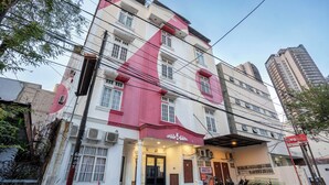 A multi-story building with a red and white facade, a covered entrance, and several motorcycles parked in front. - Tamastu House Pasar Baru Jakarta (Jakarta)