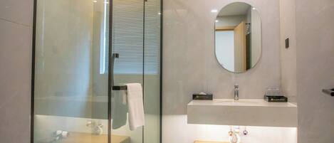 A modern bathroom with a glass-enclosed shower, a round mirror, and a wooden vanity with a sink.