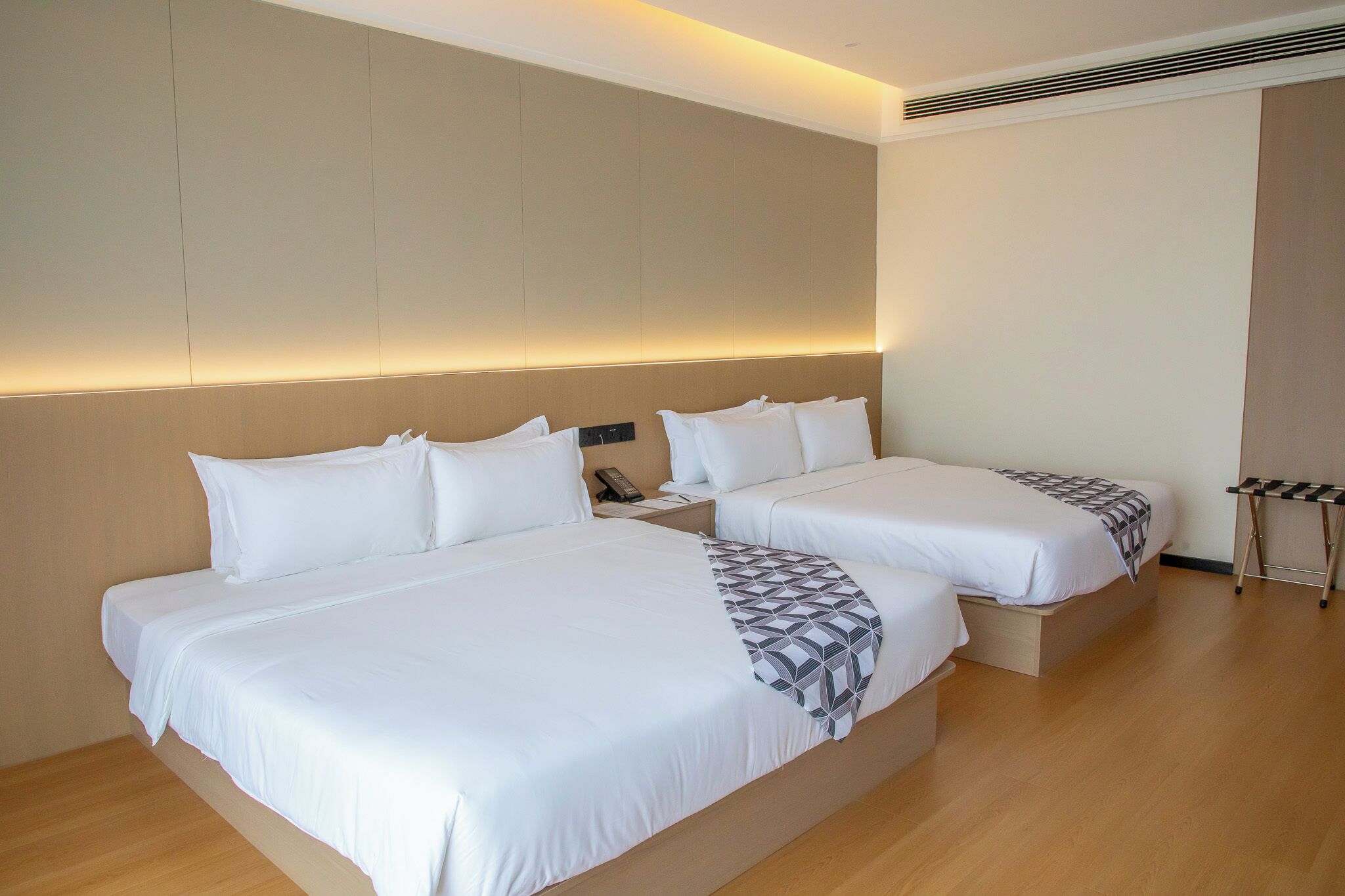 Habitación de hotel con dos camas, una mesita de noche con teléfono y una pequeña mesa con una silla.