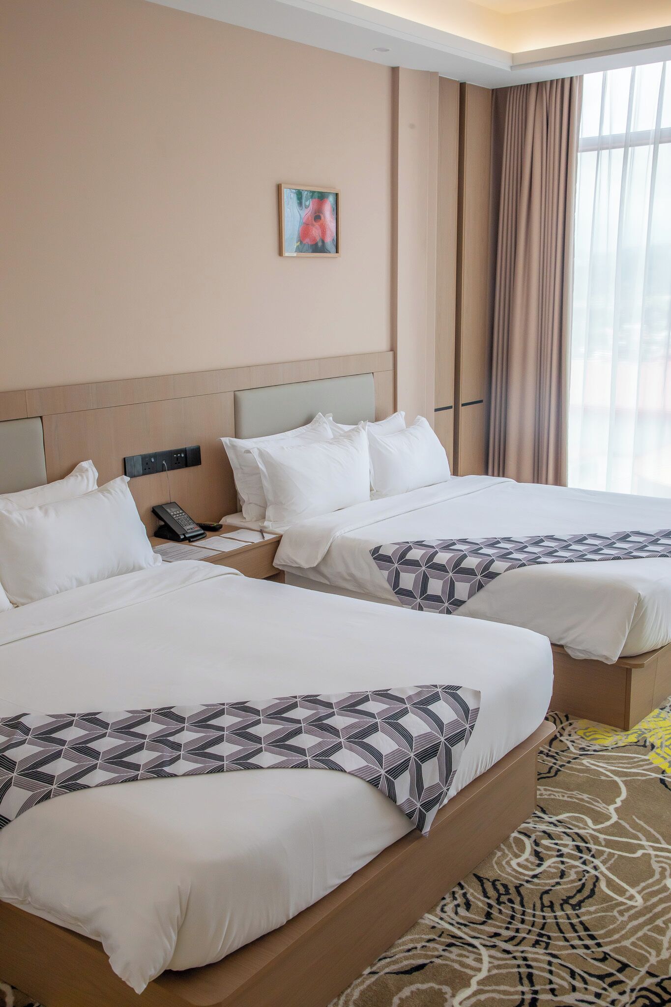 Two twin beds with white bedding, a bedside phone, and a painting on the wall.