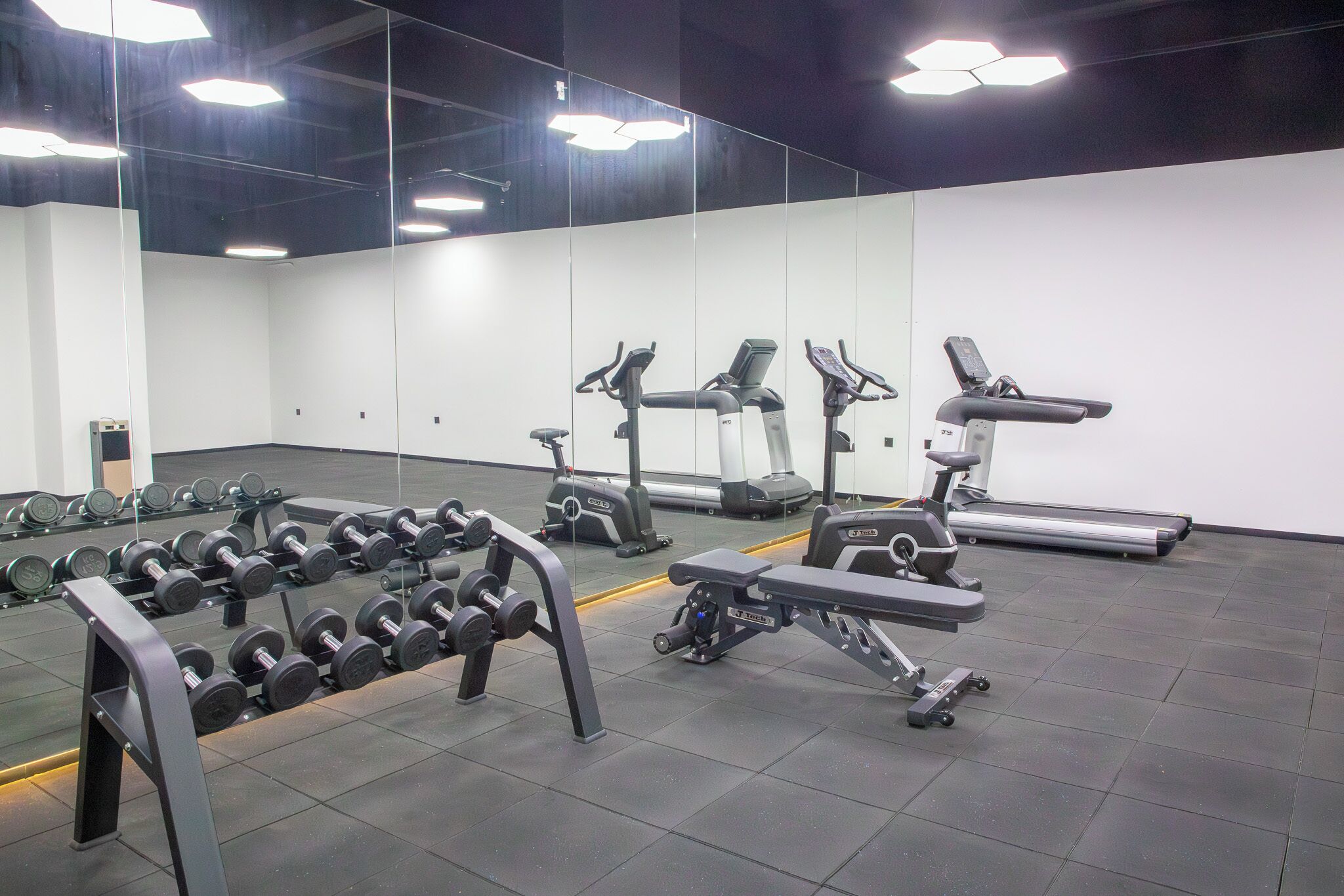 A gym with exercise equipment, a mirrored wall, and a clean, modern design.