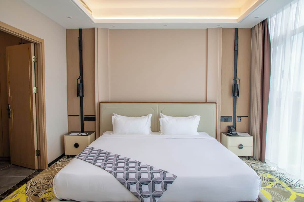 Ein Hotelzimmer mit einem großen Bett, zwei Nachttischen und einer Tür.