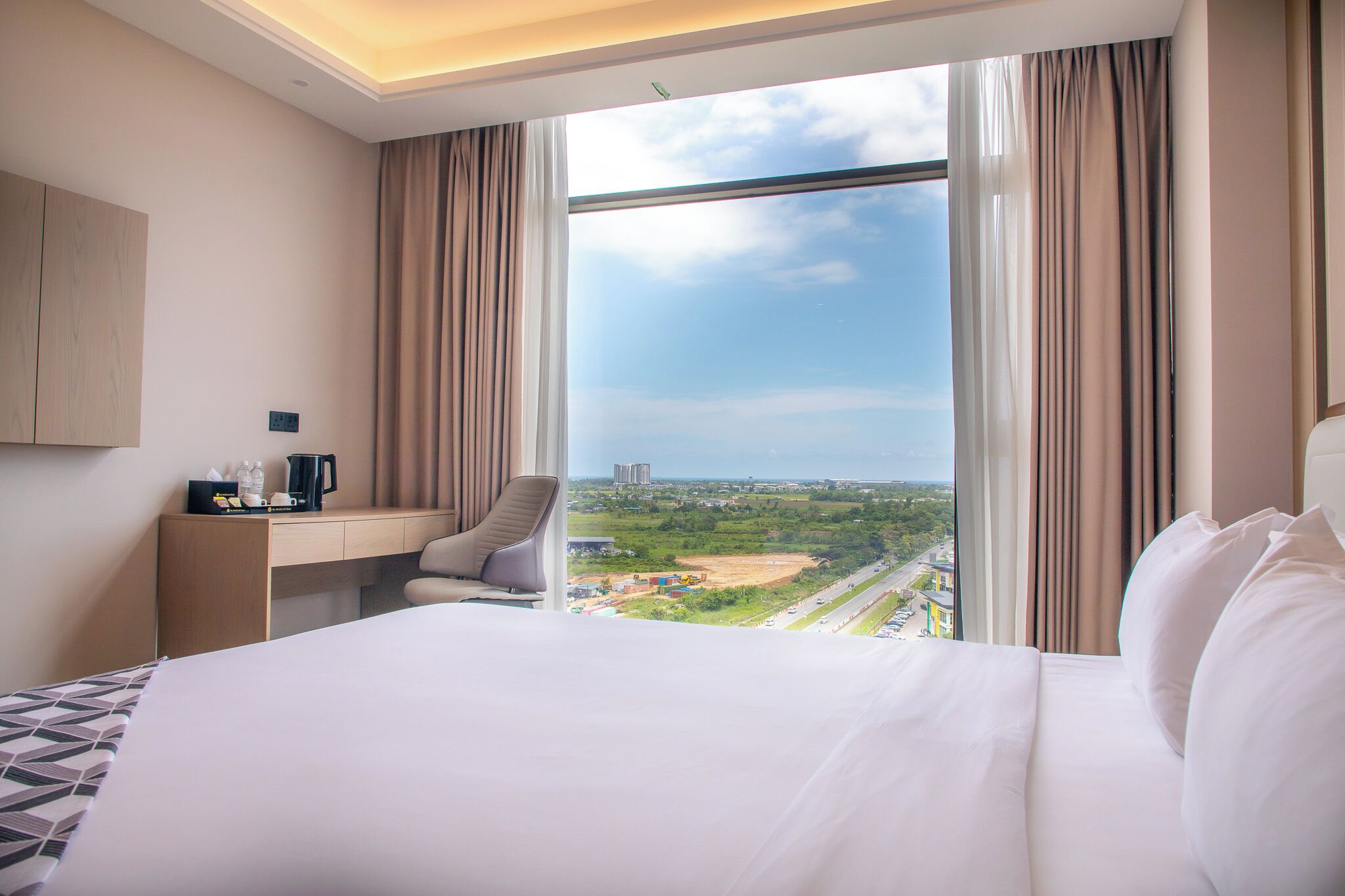 Une chambre d’hôtel avec un grand lit, un bureau, une chaise et une vue sur le paysage urbain.