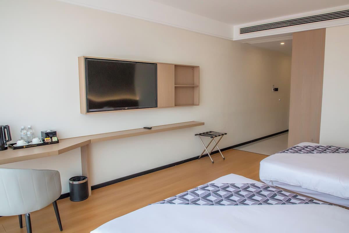 Ein Hotelzimmer mit einem Bett, einem Schreibtisch mit Flachbildfernseher, einem Sessel und einem kleinen Tisch mit Toilettenartikeln.