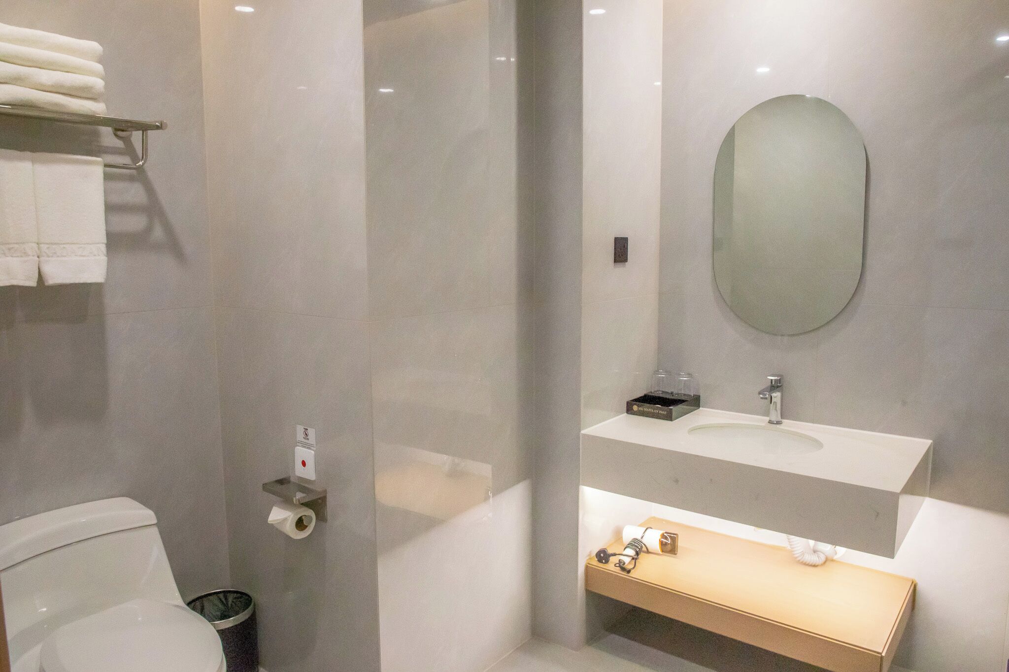 A modern bathroom with a toilet, a sink, a mirror, and a towel rack.