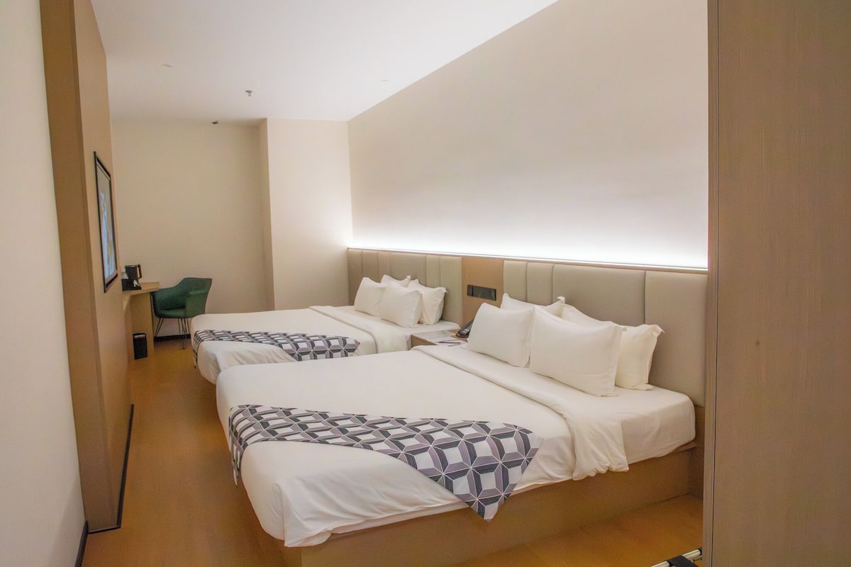 Ein Hotelzimmer mit zwei Betten, einem Schreibtisch und einem Stuhl.