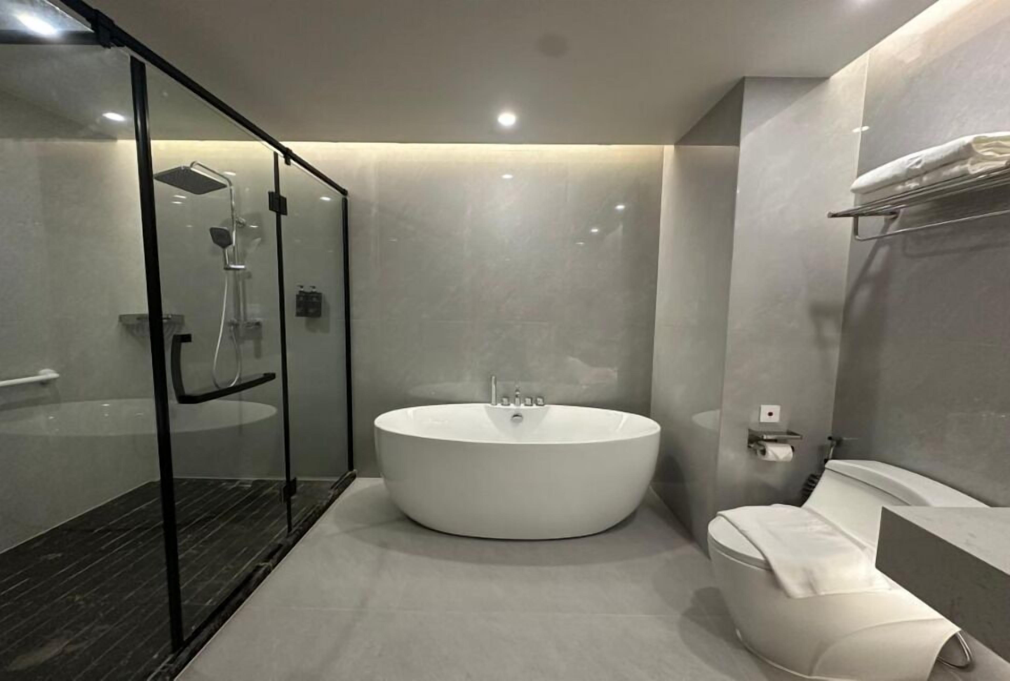 Um banheiro moderno com uma banheira independente, um chuveiro com box de vidro e um espaço separado para o vaso sanitário.