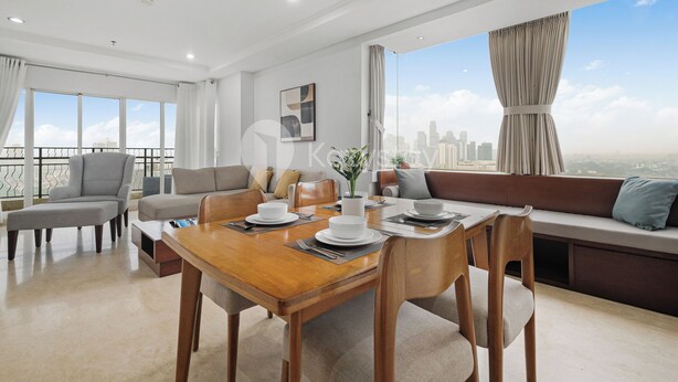 A modern living room with a dining area, large windows with city views, and a balcony.