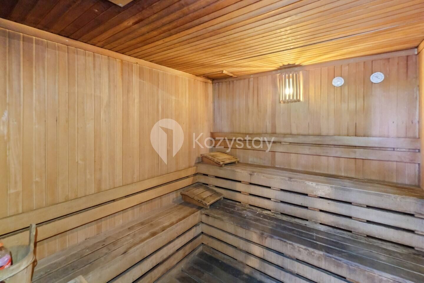En sauna med træbænke og skråt gulv, trævægge og et loft med træbjælker.