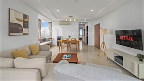 A modern living room with a sofa, coffee table, and a TV displaying 'NETFLIX'.
