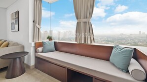 A modern living room with a large window, a sofa, a small table, and a city view.
