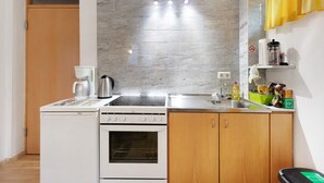 Une cuisine de taille réduite équipée d’une cuisinière Bosch, d’un évier et d’un four à micro-ondes.