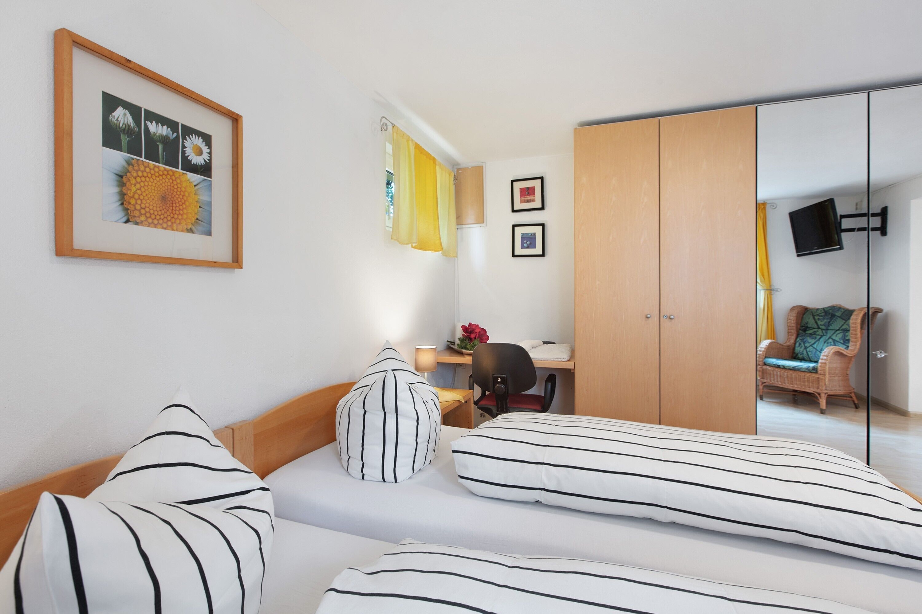 A hotel room with a bed, a desk, a chair, a wardrobe, and a television.