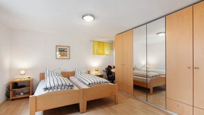 Une chambre avec deux lits, une armoire, un bureau et un miroir.