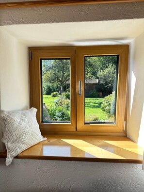 Une pièce avec un banc en bois et un coussin blanc tricoté.