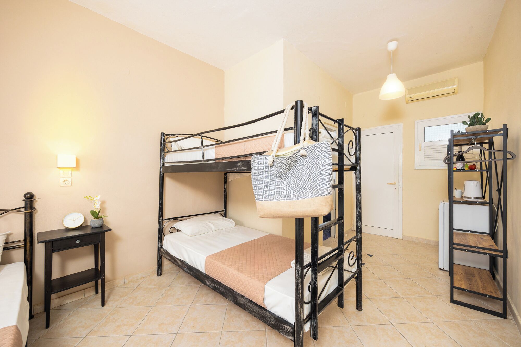 A bunk bed room with a bedside table, a hanging bag, and a shelf with items.