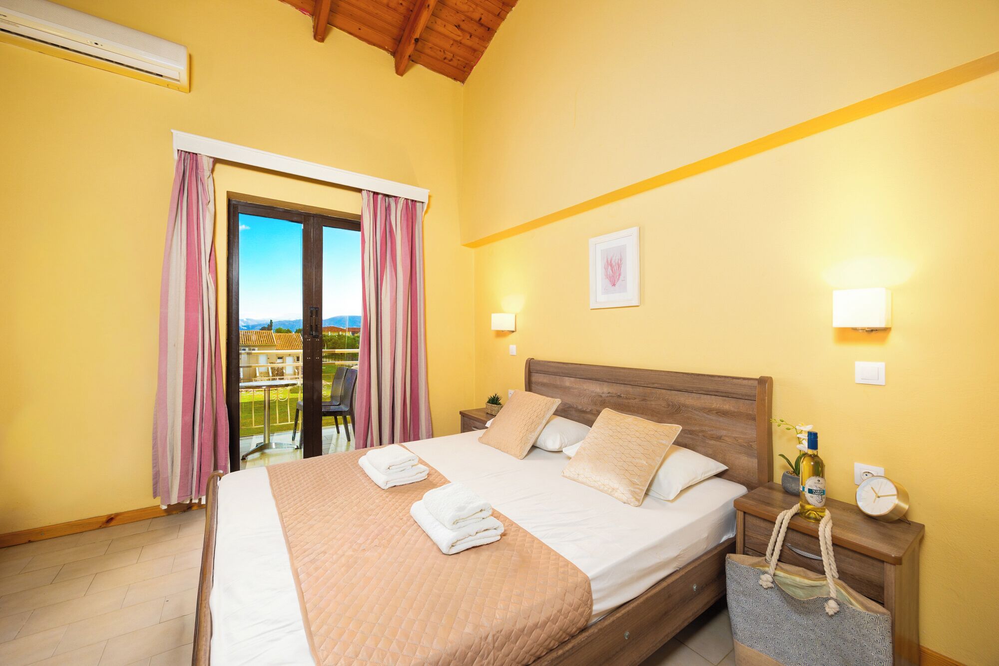 Une chambre d’hôtel comprenant un lit, des tables de chevet, une commode, une fenêtre avec des rideaux et une vue sur l’extérieur.