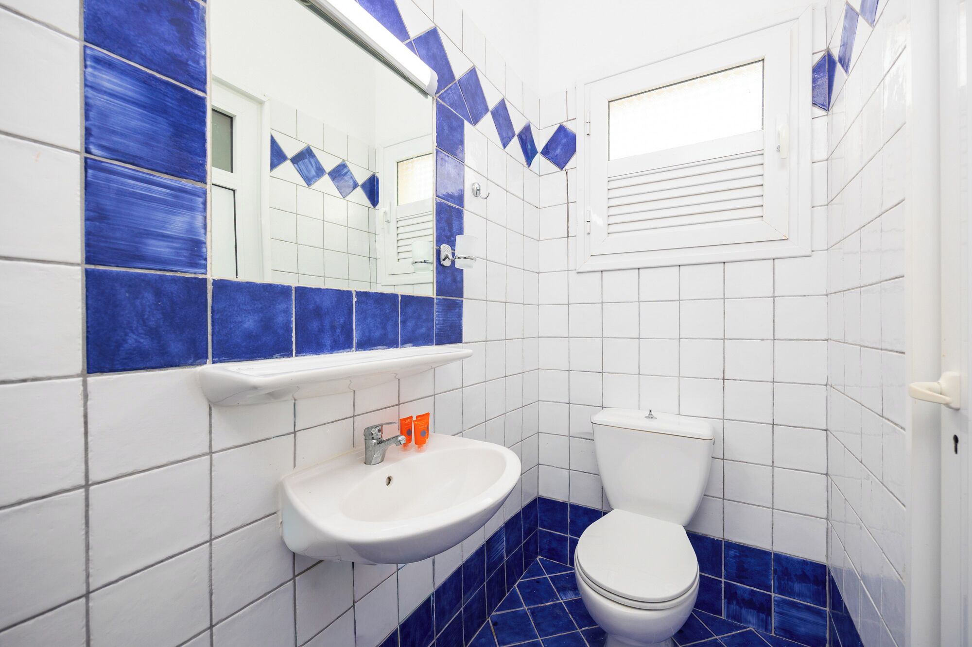 A bathroom with a white sink, blue-tiled floor, and a white toilet.