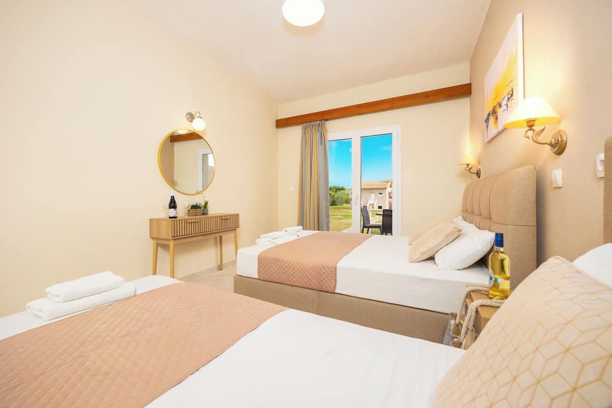 A hotel room with two beds, a wooden console table, a mirror, and a view of the outdoors.