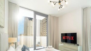 A hotel room with a large window, a flat-screen TV, a bed, and a nightstand. - LUX Contemporary Suite with Full Marina View 3 (Dubai)