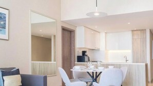 A modern living room with a dining area, a kitchen, and a large mirror. - LUX Contemporary Suite with Full Marina View 3 (Dubai)