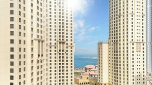 A high-rise building with multiple floors and a view of the sea in the background. - LUX Contemporary Suite with Full Marina View 3 (Dubai)
