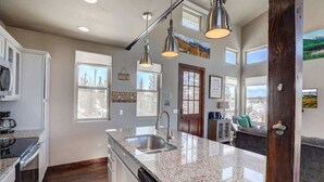 A spacious kitchen with granite countertops, stainless steel appliances, and pendant lighting. - Stunning Views from a Unique Mountain Cabin! (Jefferson)
