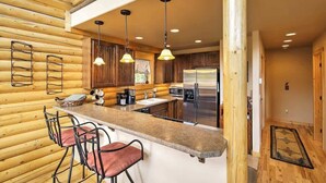 A modern kitchen with wooden walls, a bar area, and stainless steel appliances.