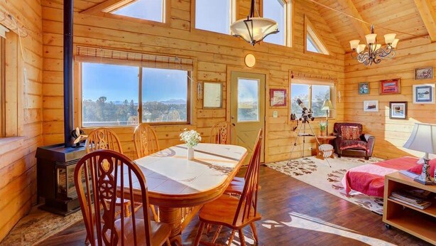 Una cabaña de madera espaciosa con comedor, sala de estar y un dormitorio.