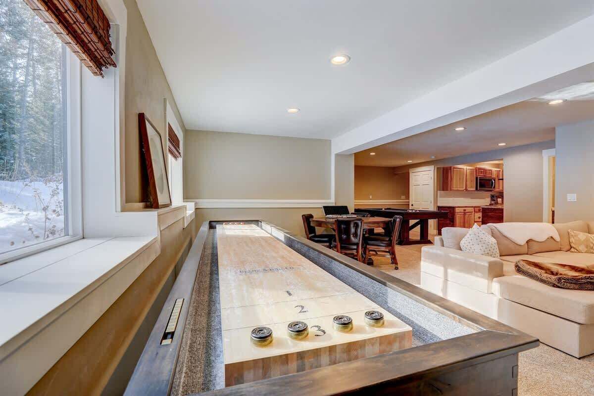 Una mesa de shuffleboard en una sala de estar moderna con vistas a un paisaje nevado a través de amplios ventanales.