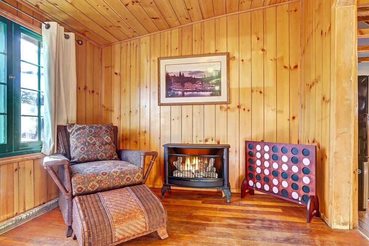 A cozy room with wooden walls, a fireplace, a wicker sofa, and a framed picture on the wall.