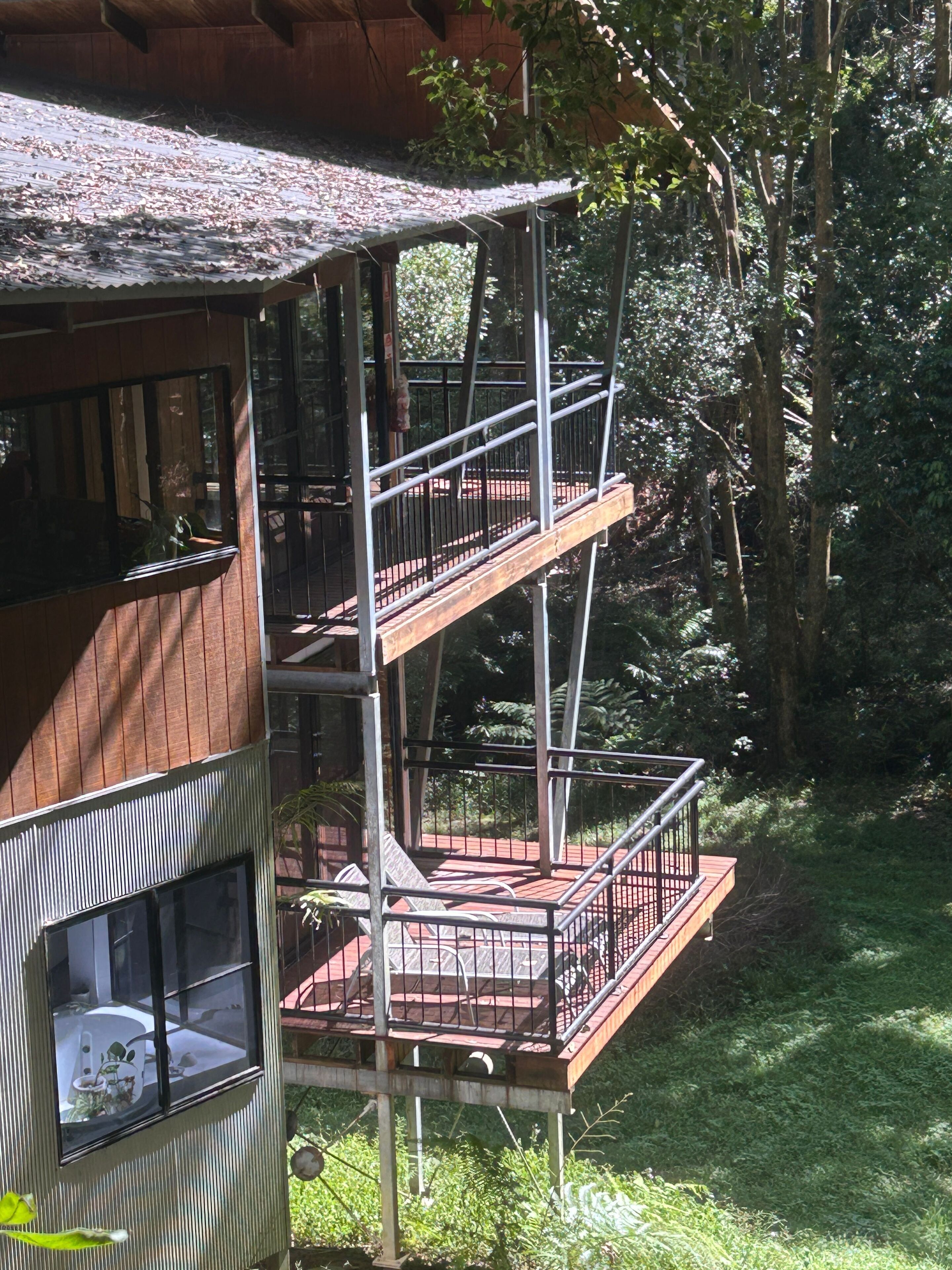 A multi-level wooden structure with balconies, surrounded by trees.